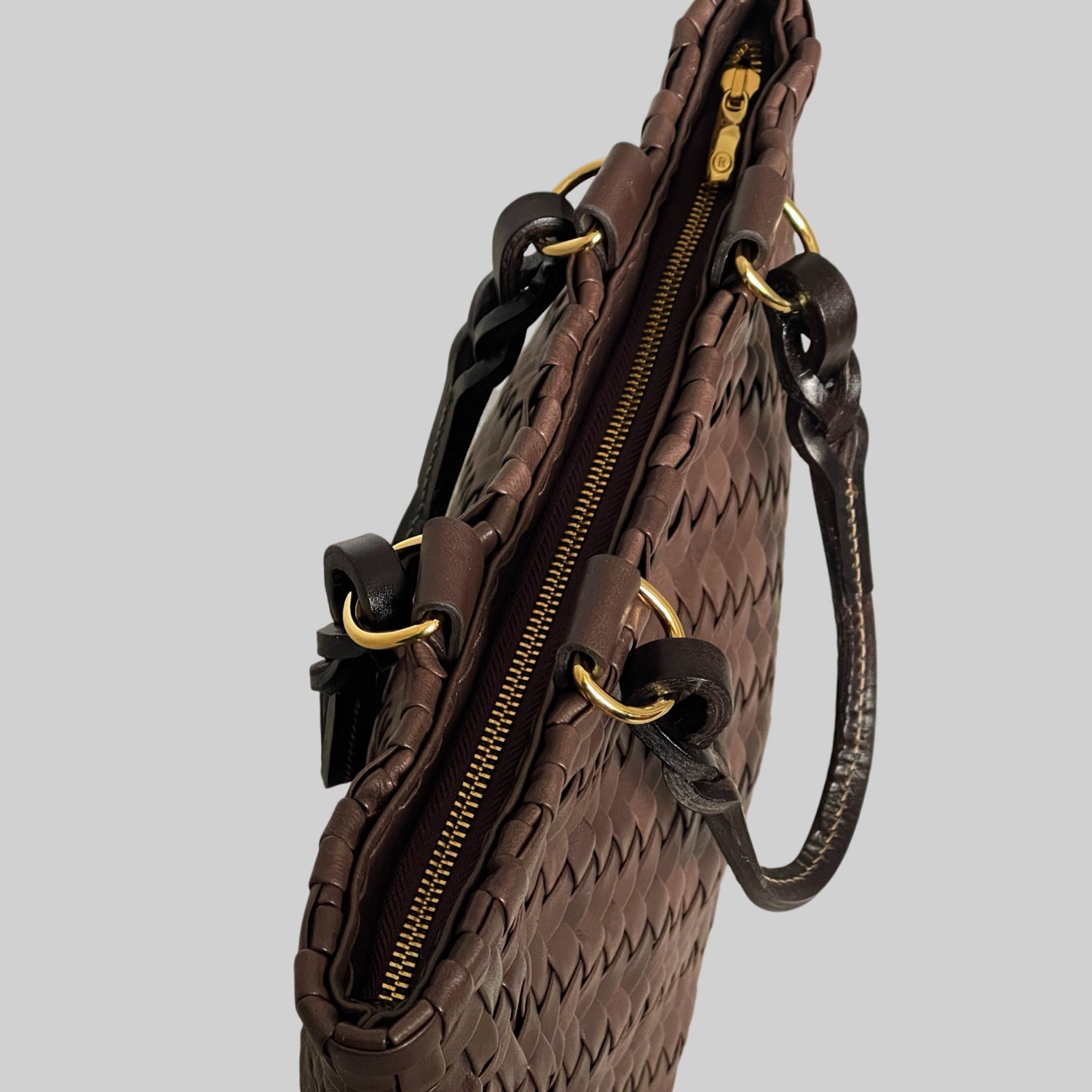 Ribichini Safari Lady-vesken i brunt, med flettet lammeskinn og glidelås, kombinerer stil og funksjonalitet på en elegant måte.