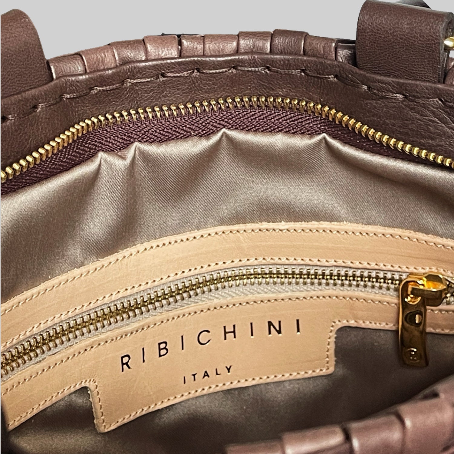 Bildet viser innsiden av en Ribichini Safari Lady skinnveske i brunt, med en elegant glidelåslomme i gullfarge og den ikoniske R-logoen som legger til et preg av luksus.