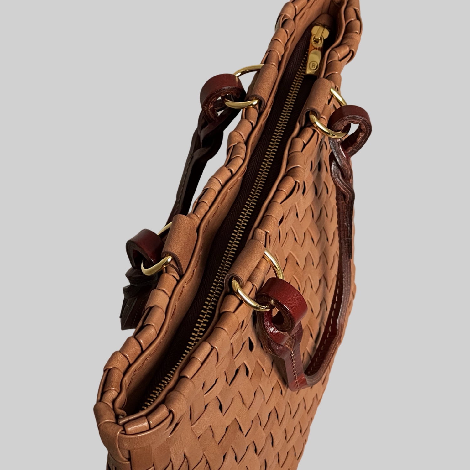 Ribichini Safari Lady-vesken i cognac, med flettet lammeskinn og glidelås, kombinerer stil og funksjonalitet på en elegant måte.