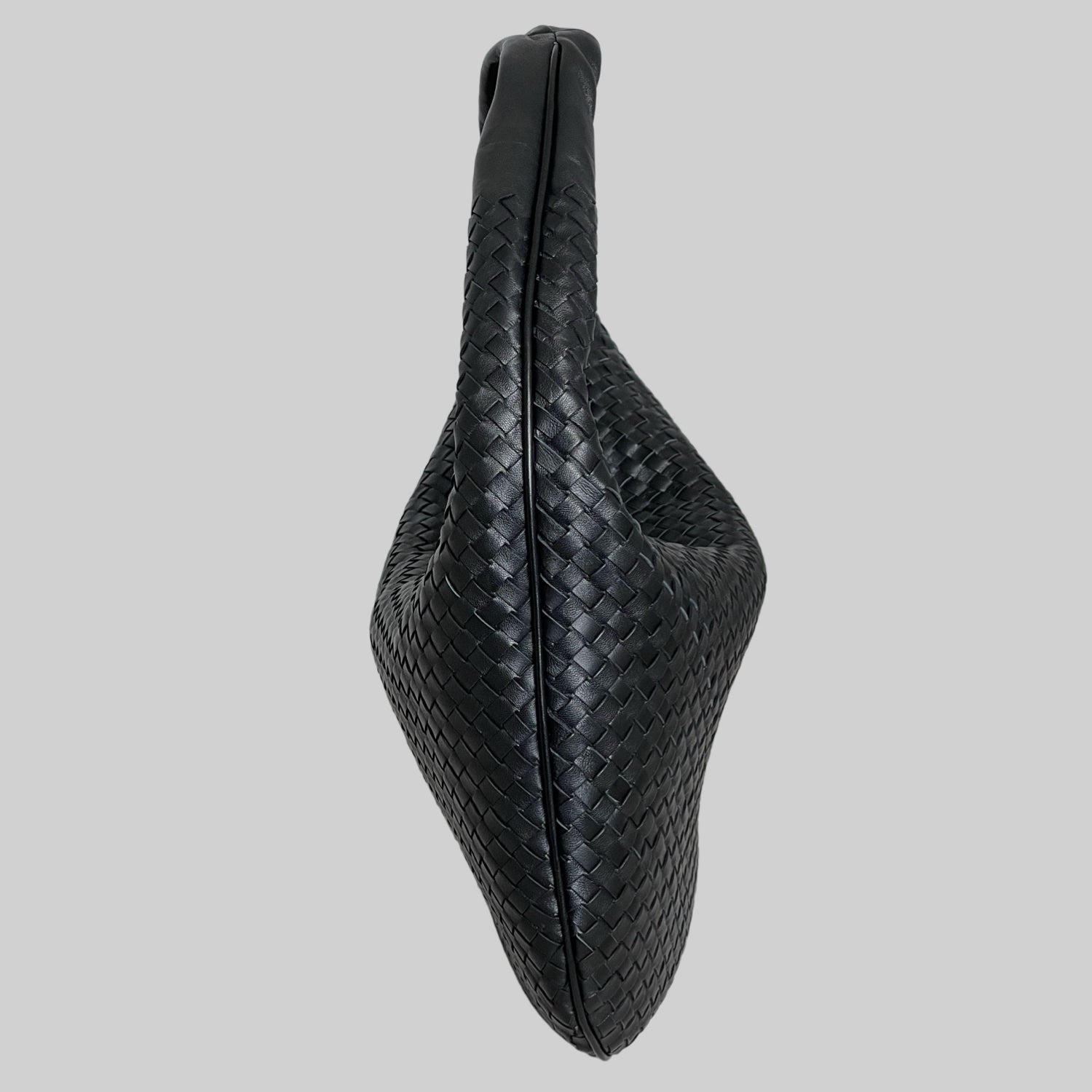 Sideprofil av Ribichini Isola-vesken i sort, som viser det unike flettede lammeskinn og den slanke silhuetten.