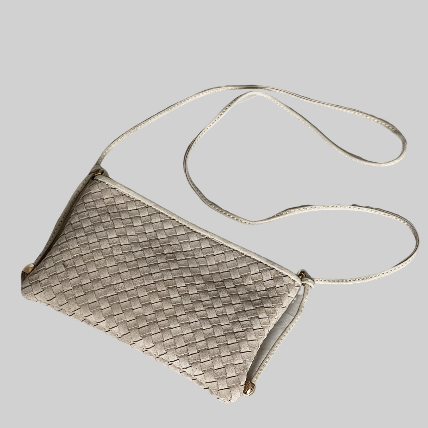 Ribichini Camper clutch i fargen sand i semsket lammeskinn med flettet design og lang skulderrem, vist ovenfra.