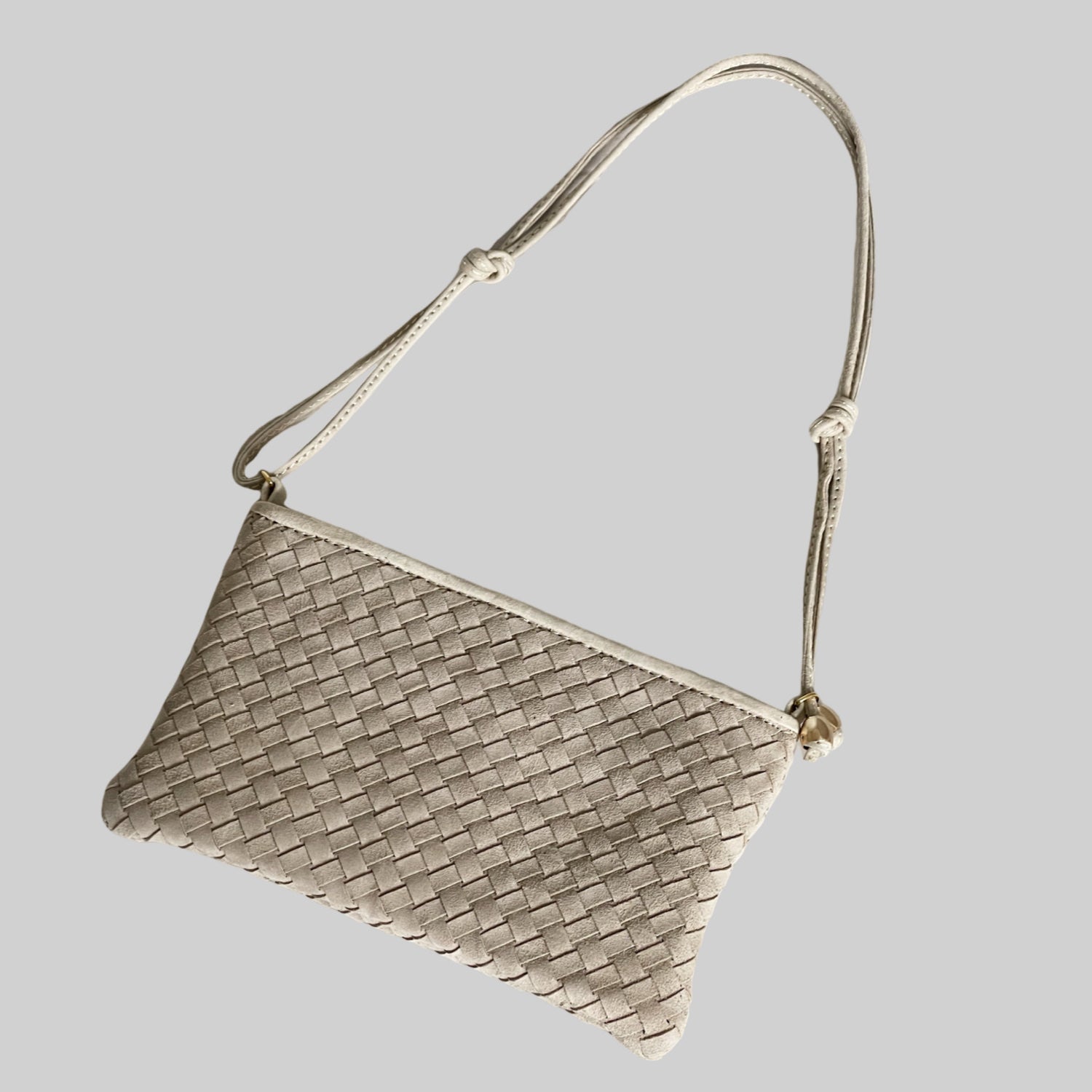 Ribichini Camper clutch i fargen sand i semsket lammeskinn med flettet design og gulldetaljer, vist ovenfra med skulderrem.