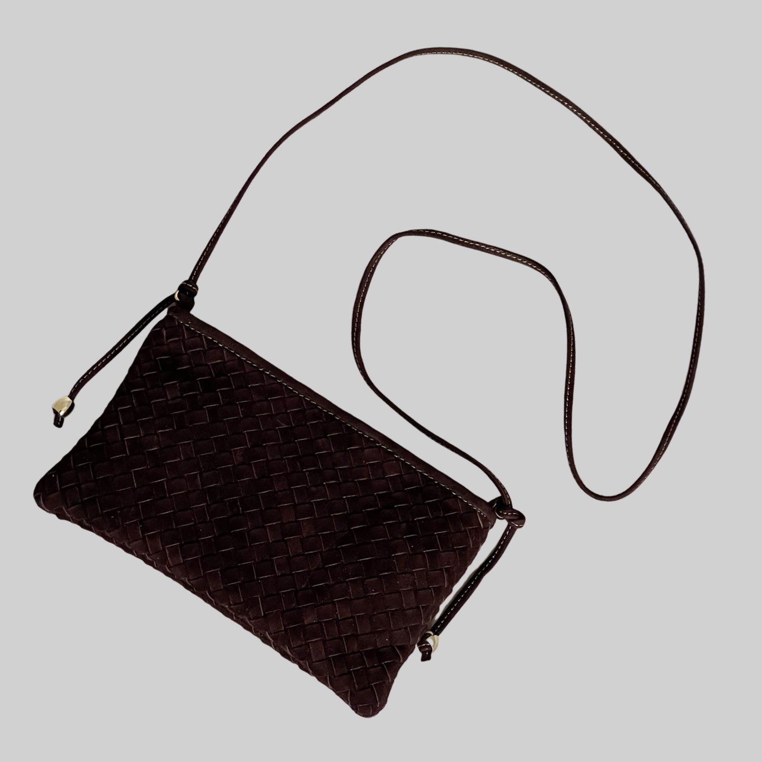 Ribichini Camper clutch i semsket sjokoladebrunt skinn, med lang skulderstropp og justerbare detaljer for en elegant og tidløs stil.