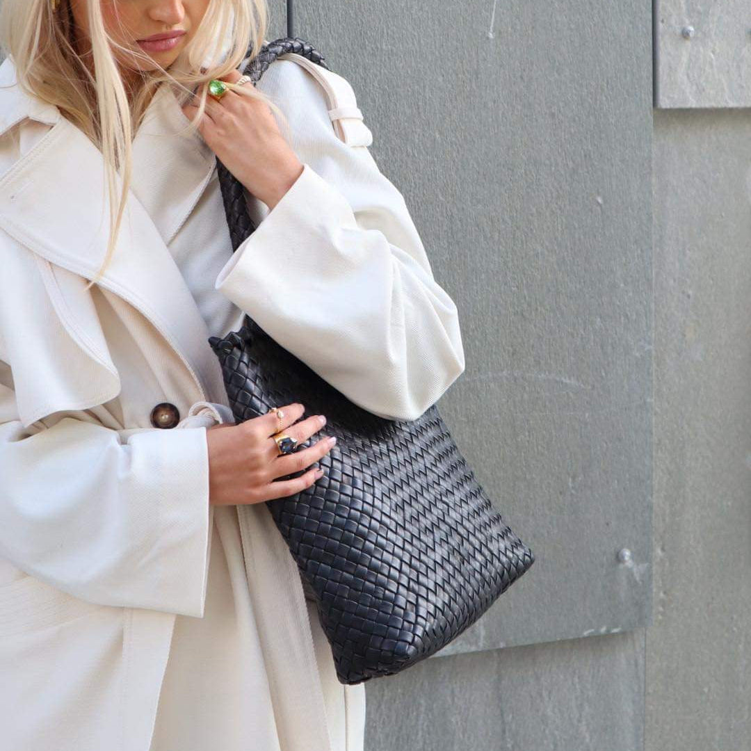 Woodstock Babe – håndflettet skulderveske i sort skinn, brukt over skulderen med flettet hank og tidløst design.