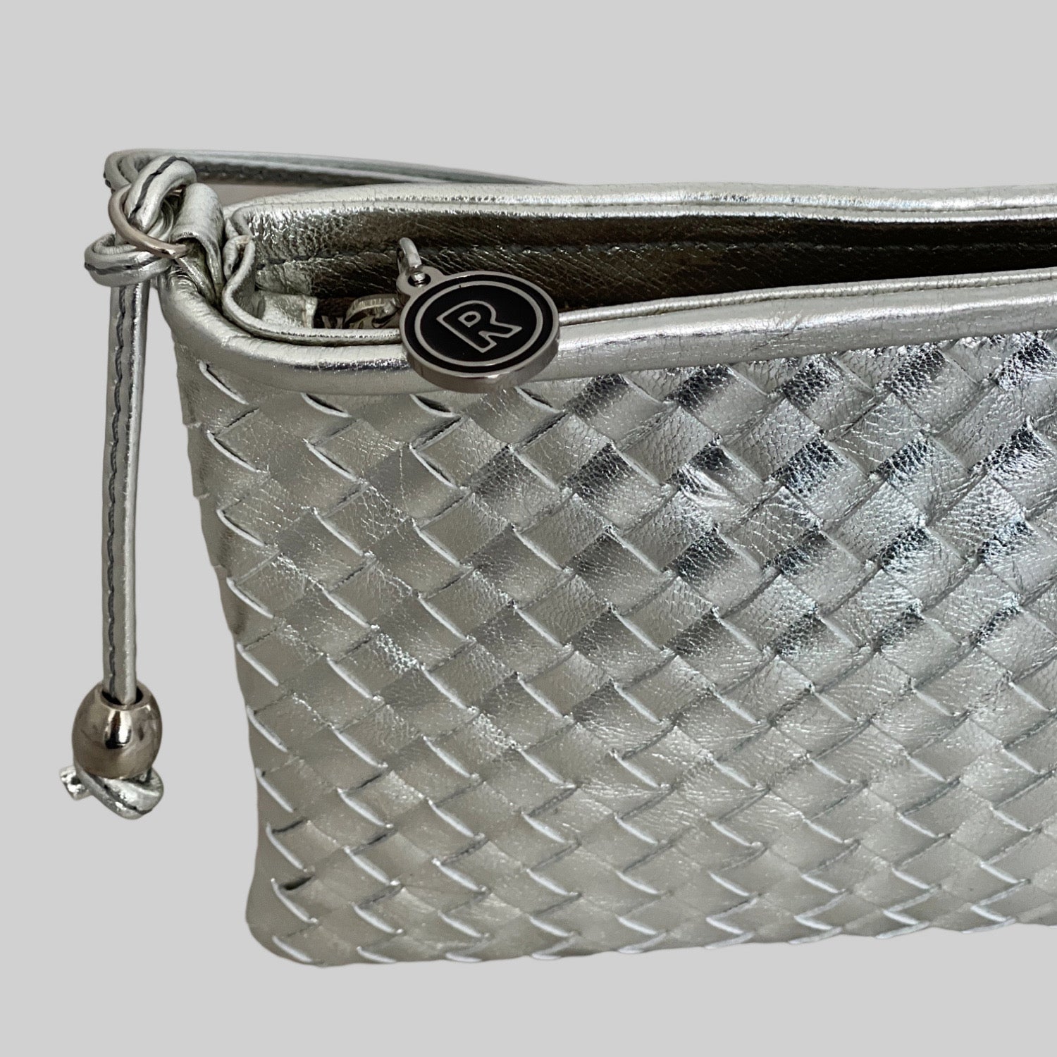  Ribichini Camper Clean Clutch i sølv: Flettet lammeskinn, sofistikert glans, ikonisk R-detaj i sølv. Elegant og stilfull.