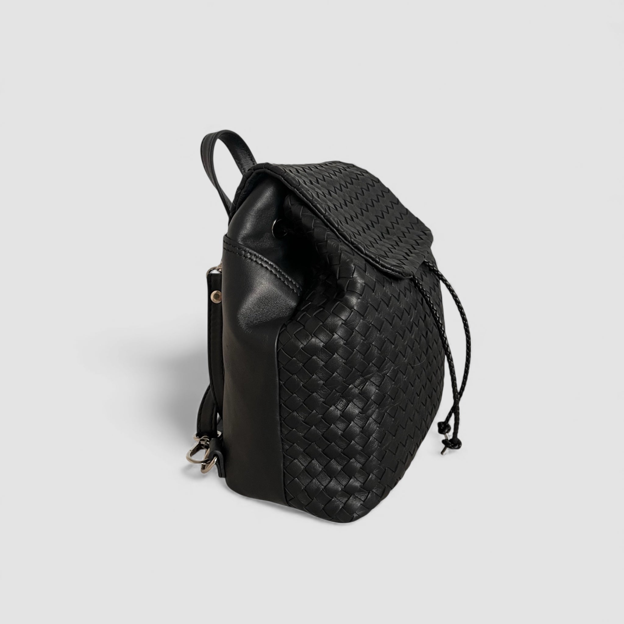 Ribichini Backpack Mini sett fra siden, i håndflettet svart italiensk skinn med snøring.