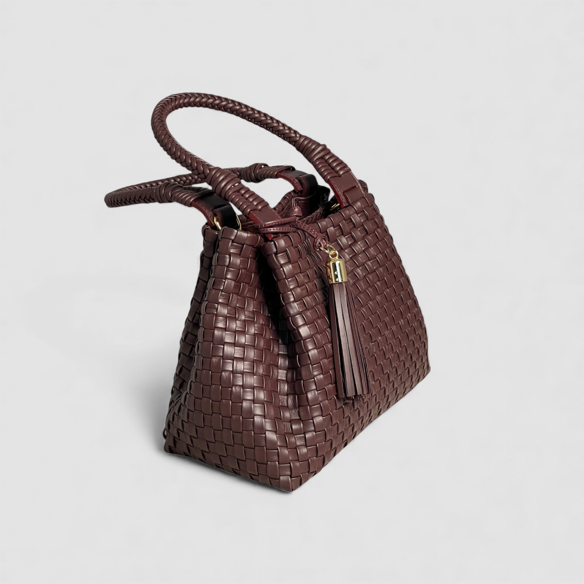 "Sophia" vesken i dyp bordeaux, sett fra siden, med flettede hanker som gir et preg av nøye håndverk og tidløs eleganse.