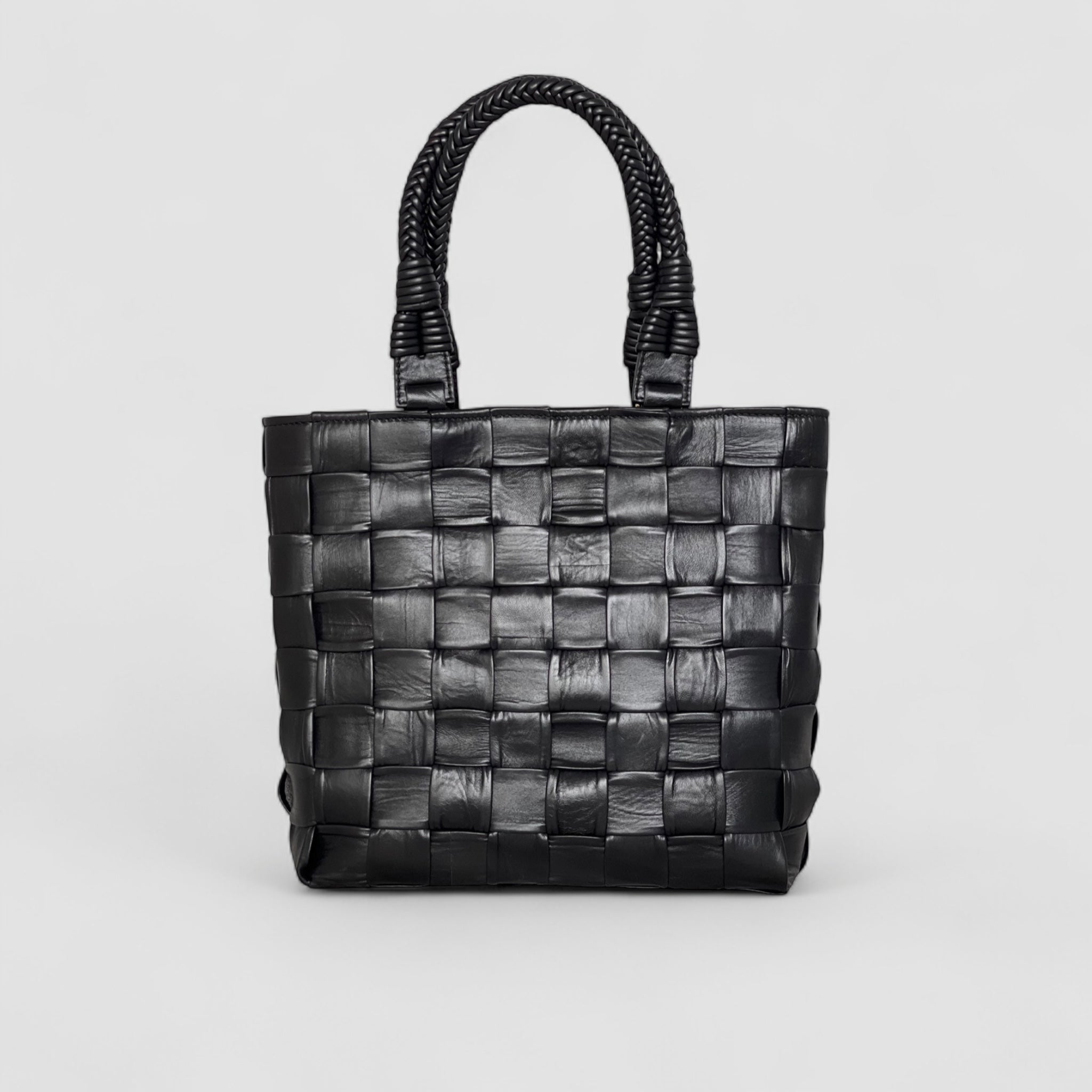 Ribichini Square Babe i sort, laget av håndflettet lammeskinn. Vesken har en unik design med store, generøse ruter og flettede hanker.