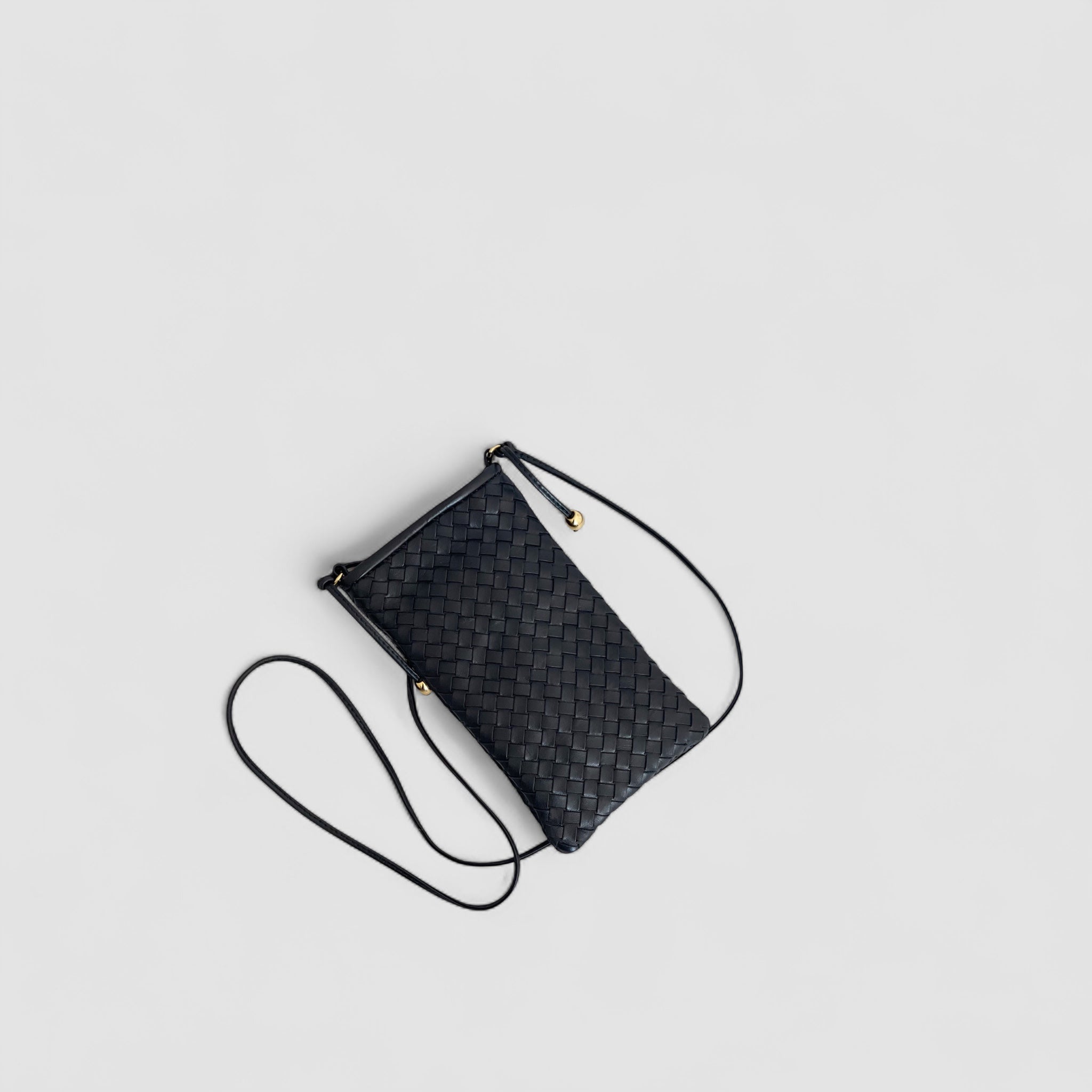 Ribichini Pocket skinnveske i sort har en tynn skulderstropp med gulldetaljer som følger med vesken.