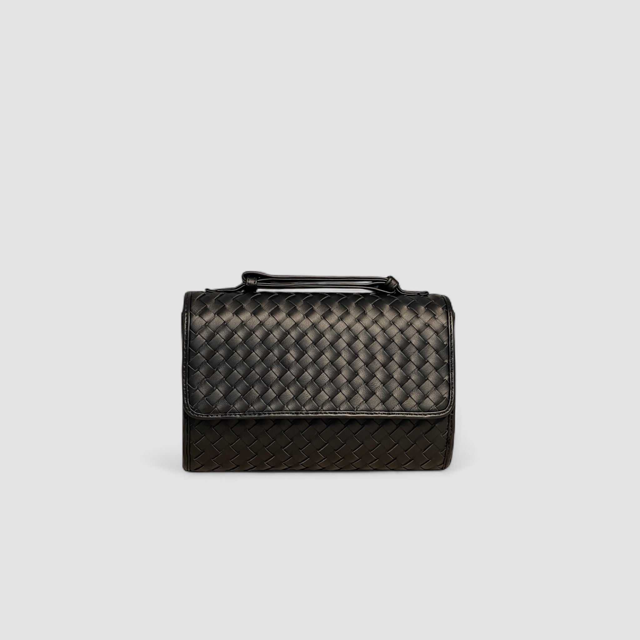 Frontbildet av Ribichini Primadonna-clutchen viser dens sorte flettet lammeskinn og tidløse eleganse gjennom glatt silhuett og vintage-inspirerte detaljer.