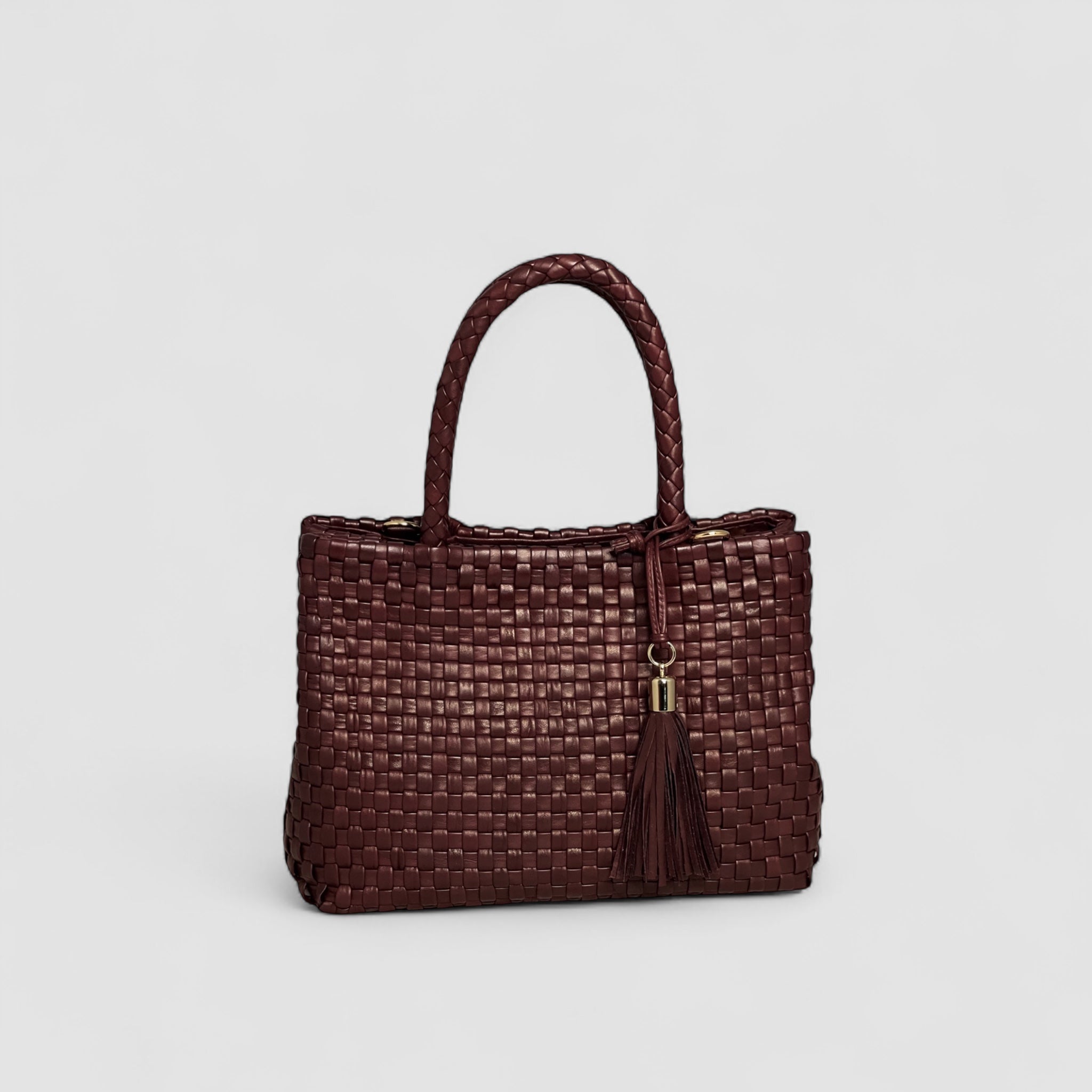 Ribichini Ginny-vesken i flettet bordeaux lammeskinn er elegant med luksuriøse gulldetaljer og dekorativ dusk. 