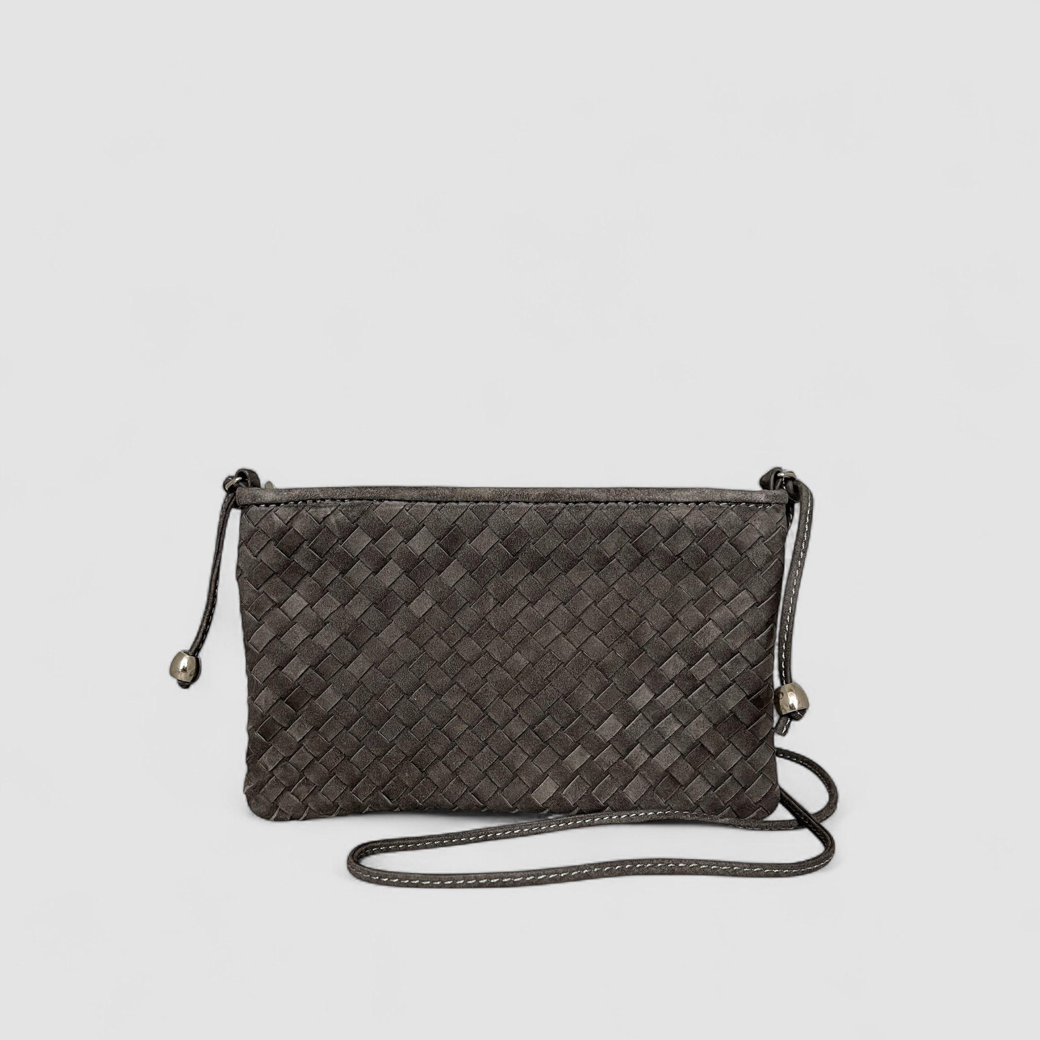 Her er en Ribichini Camper clutch i graphite. Den er laget av semsket lammeskinn, har et flettet design og sølvdetaljer, noe som gjør den unik og fin.