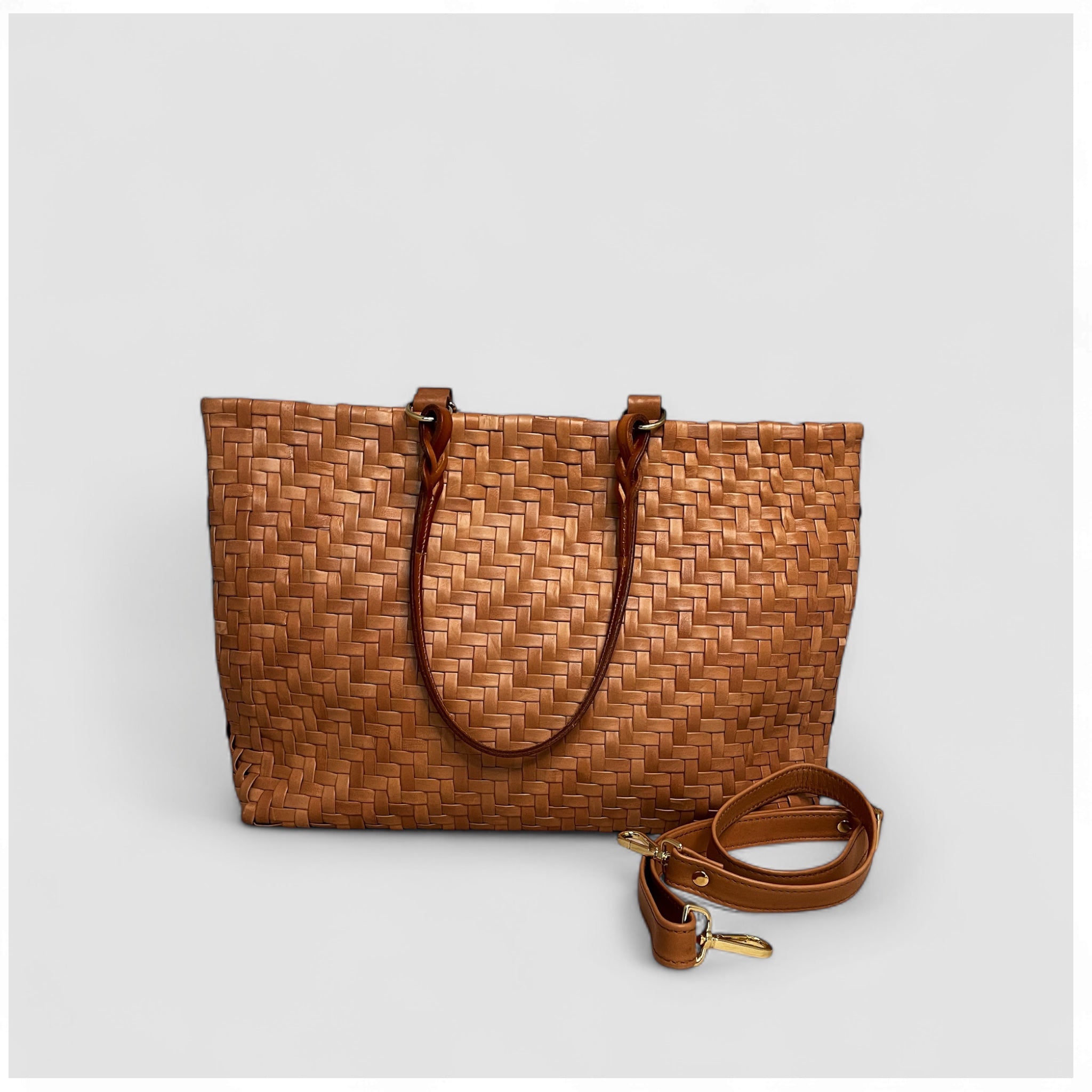 På bildet kan man se den avtagbare skulderstroppen med elegante gulldetaljer som følger med en Ribichini Safari-veske i cognacfarge.