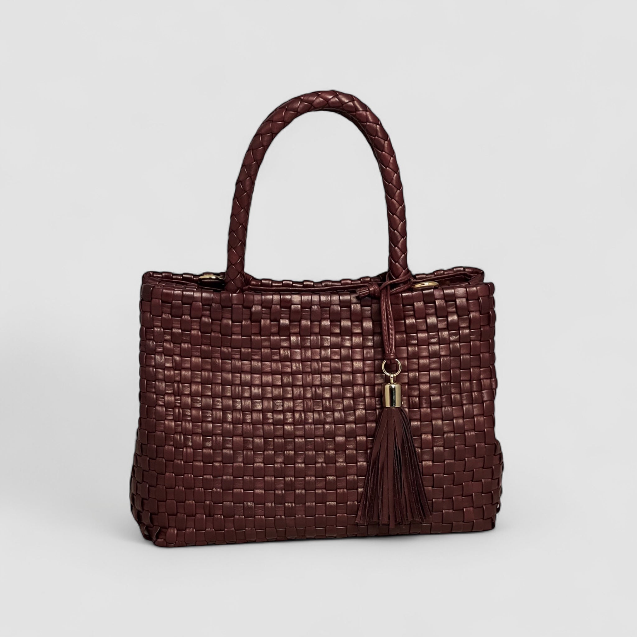Ribichini Ginny-vesken i flettet bordeaux lammeskinn er elegant med luksuriøse gulldetaljer og dekorativ dusk. 