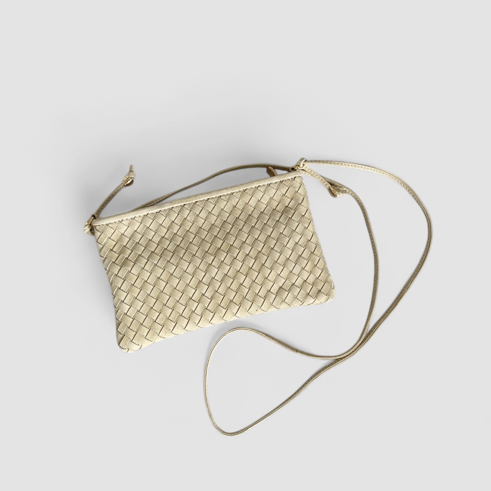 Ribichini Camper clutch i kremfarge. Den er laget av semsket lammeskinn, har et flettet design og gulldetaljer og justerbar skulderstropp.