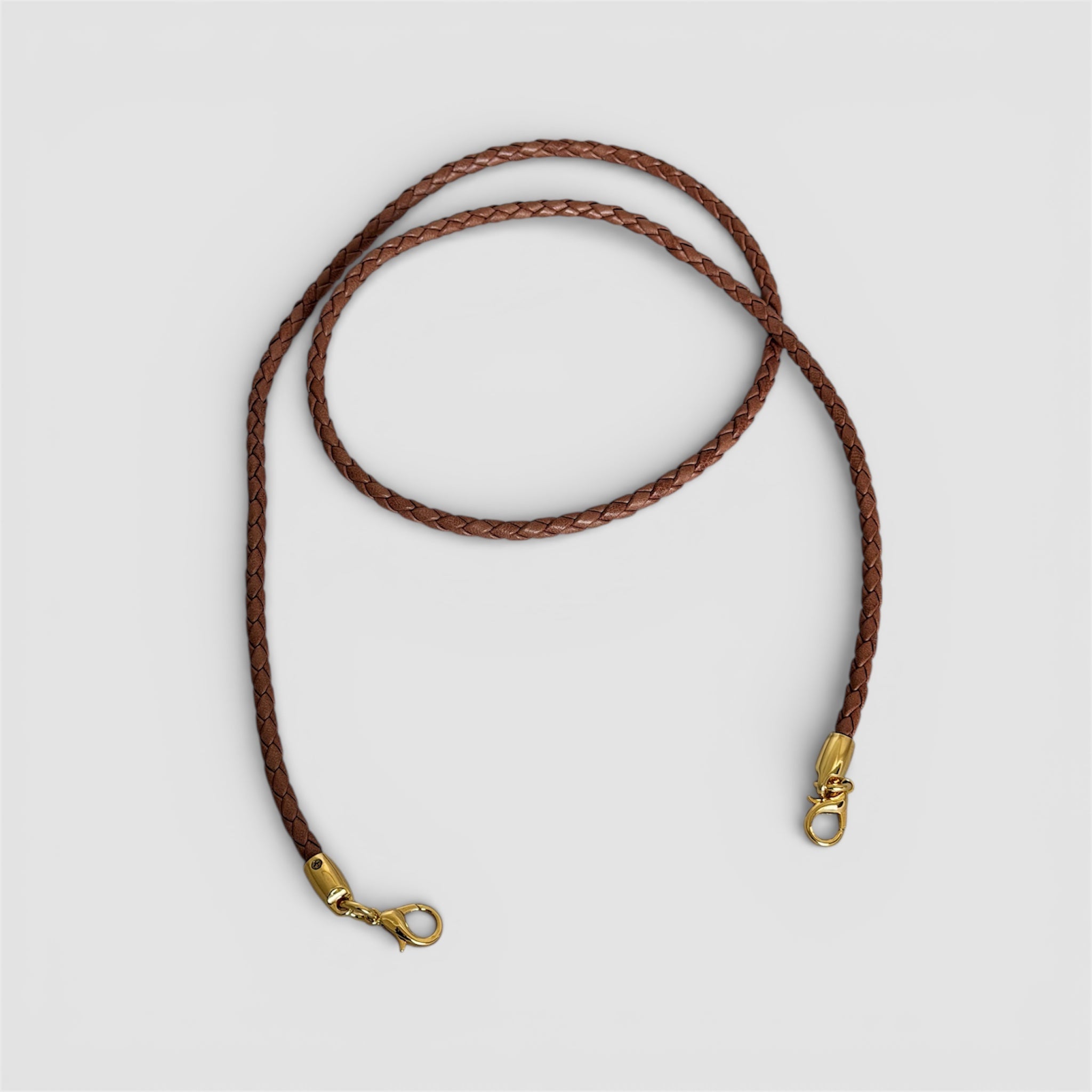 Avtagbar flettet skulderstropp i cognac skinn med gullfargede karabinkroker, håndlaget i Italia.