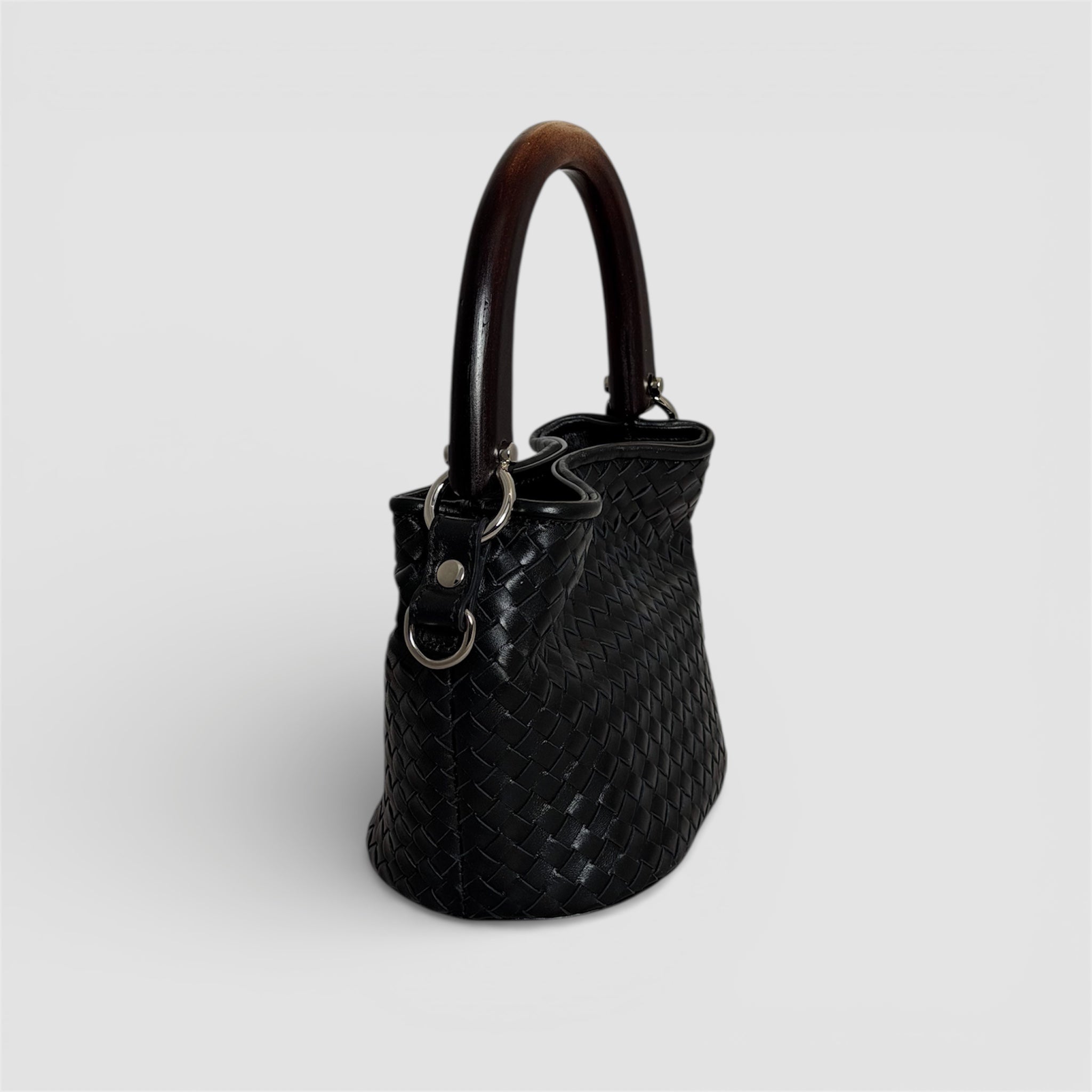 Sidevisning av Ribichini Albero veske i håndflettet sort skinn med skulpturelt trehåndtak, håndlaget i Italia.
