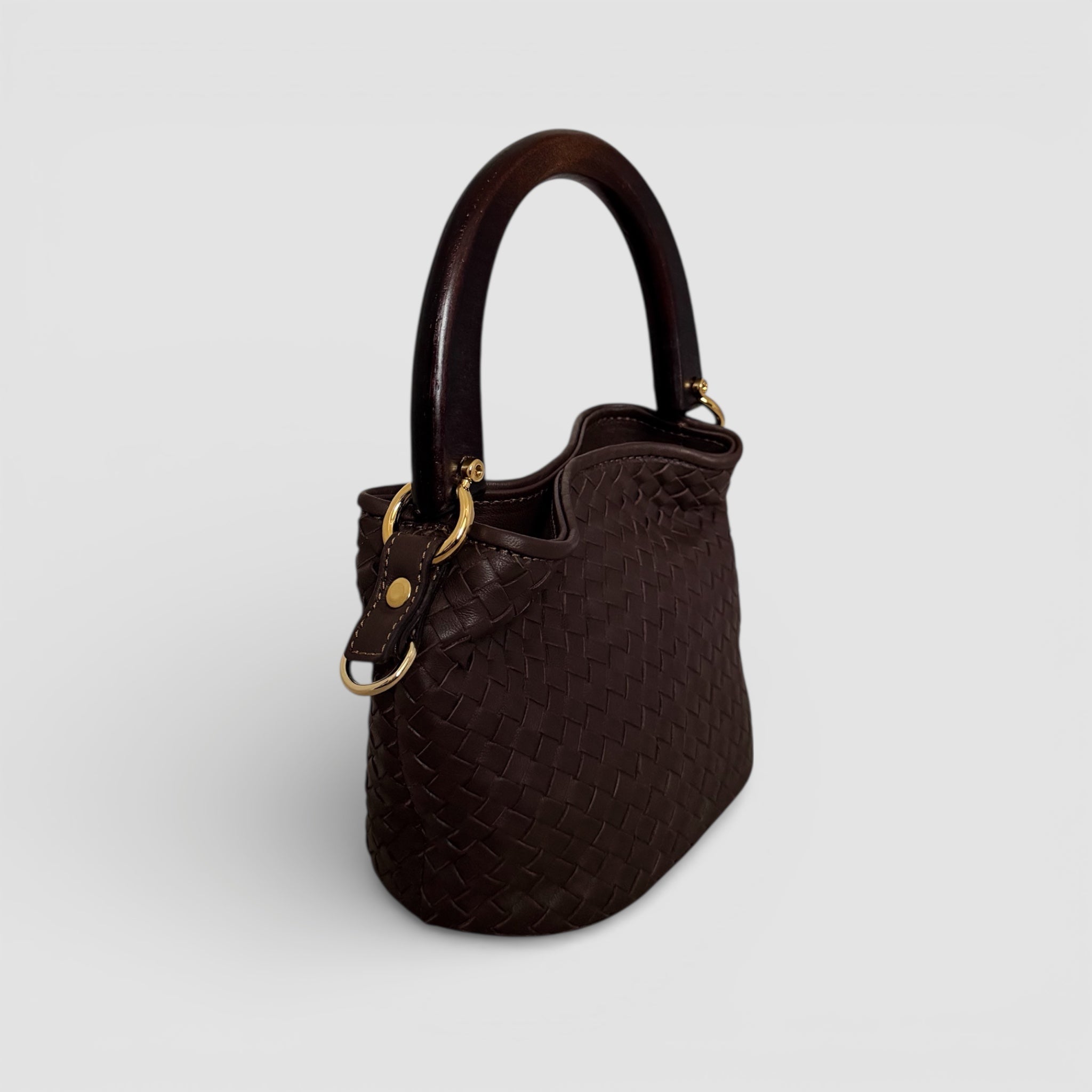 Sidevisning av Ribichini Albero veske i håndflettet brunt skinn med skulpturelt trehåndtak, håndlaget i Italia.