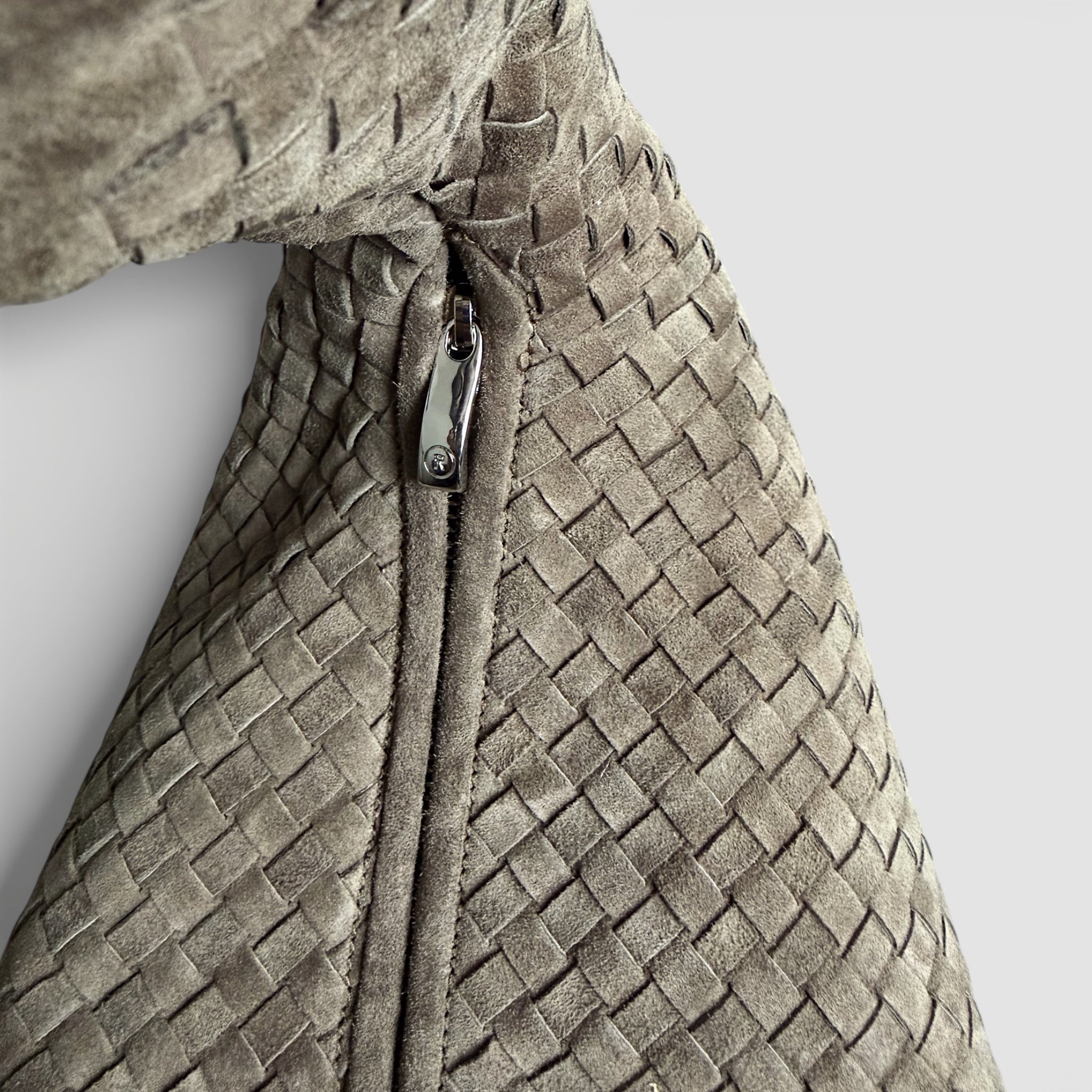 Detaljbilde av Ribichini Isola Royal Smoke i semsket skinn med håndflettet struktur og glidelåslukking.