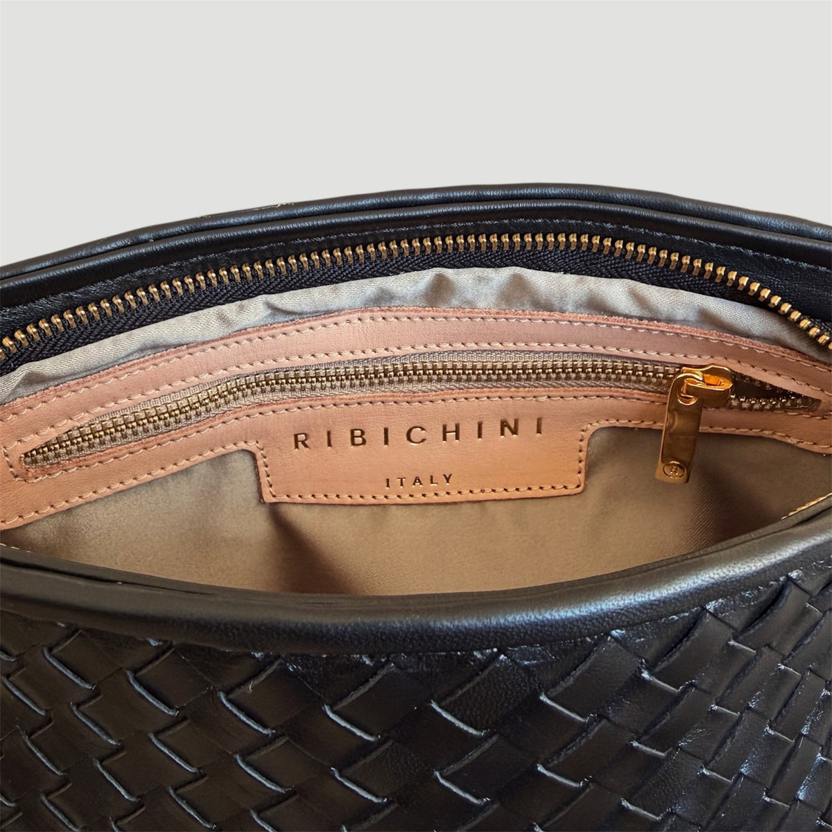 Ribichini Camper Clutch Grande Black – detaljbilde av innsiden med glidelåslomme, gullfargede detaljer og Ribichini Italy-logo.