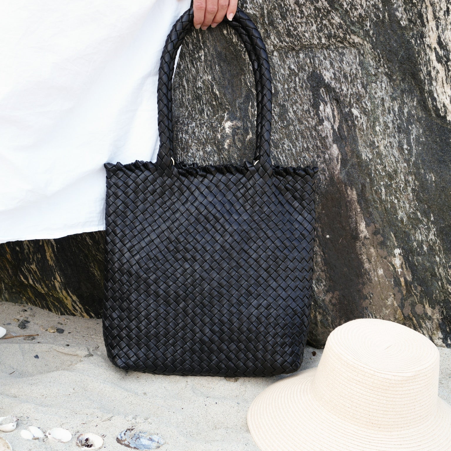 Ribichini Woodstock Babe Black håndflettet toteveske i italiensk lammeskinn på stranden.