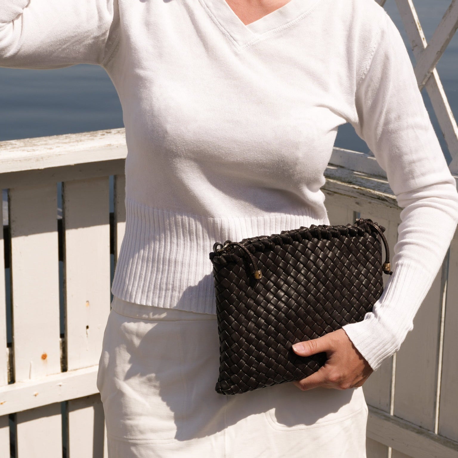 Ribichini Woodstock Clutch chocolate håndflettet clutch i italiensk lammeskinn ved sjøen.