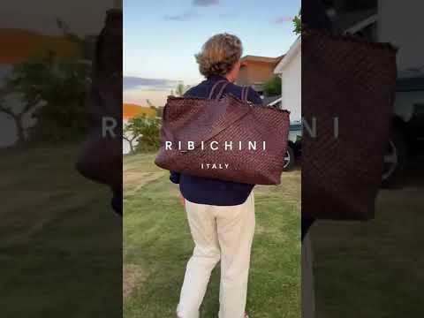 Denne videoen viser en ung mann som bærer en Ribichini Woodstock Weekend flettet skinnveske i brun og en Ribichini Crossover skinnveske i brun. Han går fra bryggen opp til sin Range Rover for å legge veskene i bagasjerommet.