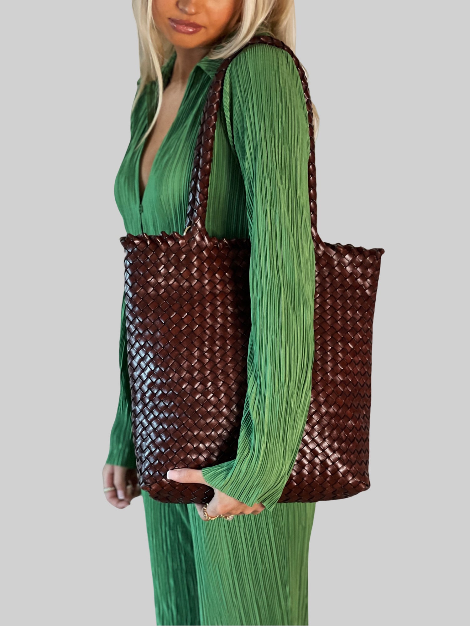 En kvinne i limegrønn silkedress bærer en Oak Ribichini Woodstock Limited Babe-veske. Vesken gir en stilig kontrast til det livlige antrekket hennes.