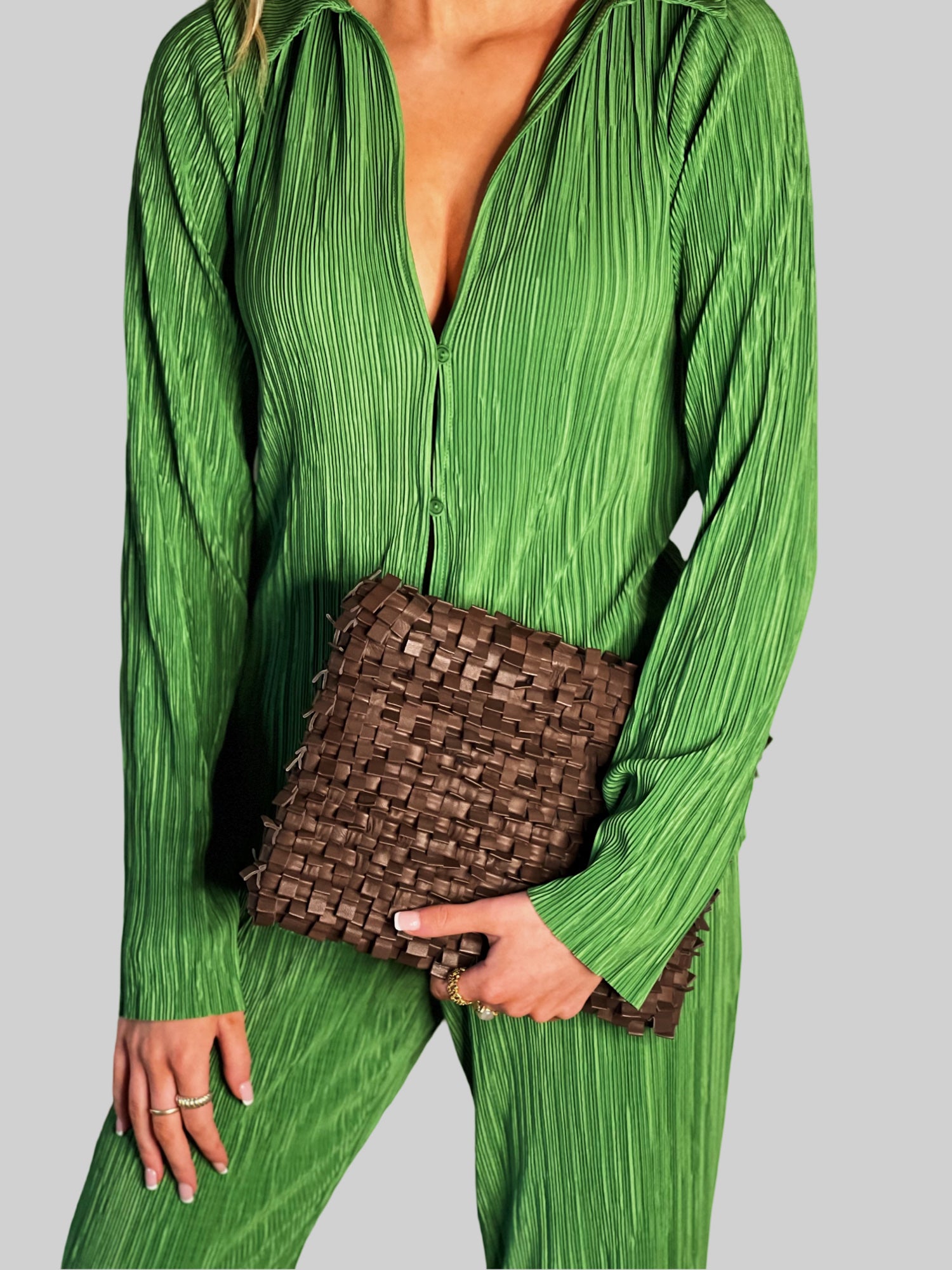 Kvinne i limegrønt antrekk bærer stolt en Ribichini Loren Clutch i brunt, et elegant tilbehør som fremhever hennes friske stil. 