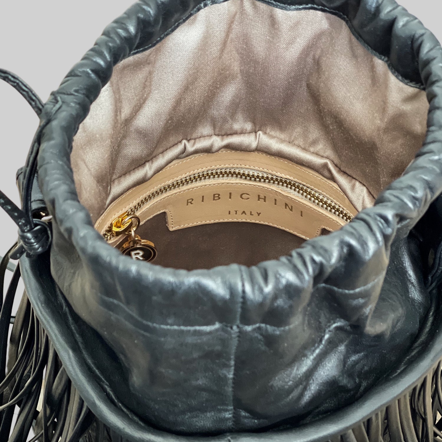 nnsiden av en sort Ribichini Bucket med glidelås og elegante gulldetaljer kombinerer stil og funksjonalitet.